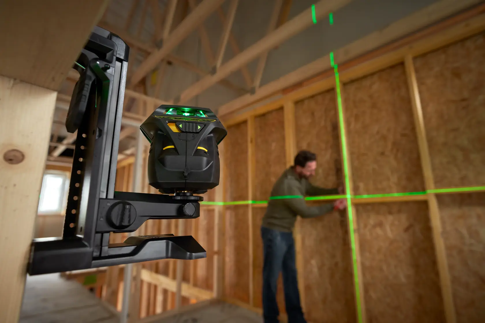 STANLEY FMHT1-77356 Laser-Nivelliergerät projiziert grüne Linien, Foto zeigt Baustellenaufbau.
