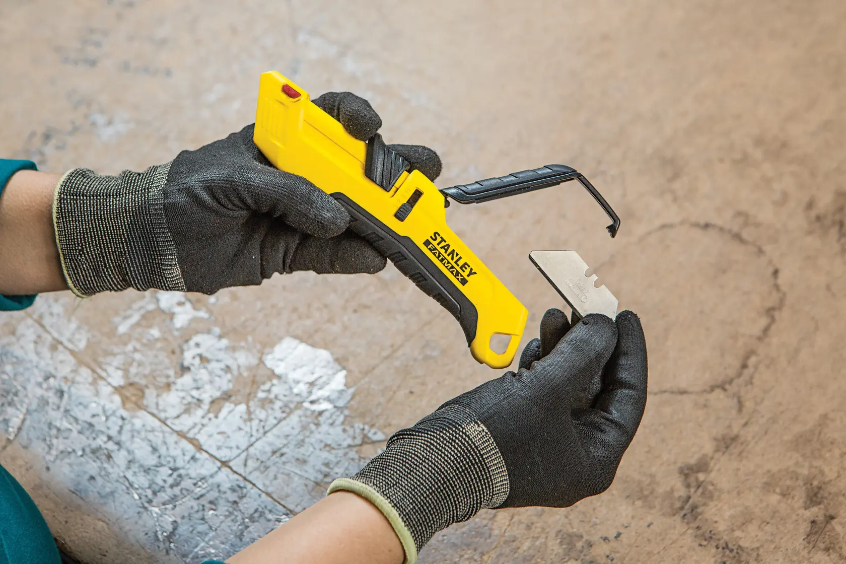 Foto von STANLEY FMHT10365-0 Universalmesser in behandschuhten Händen, Klingenwechsel, Innenbereich.