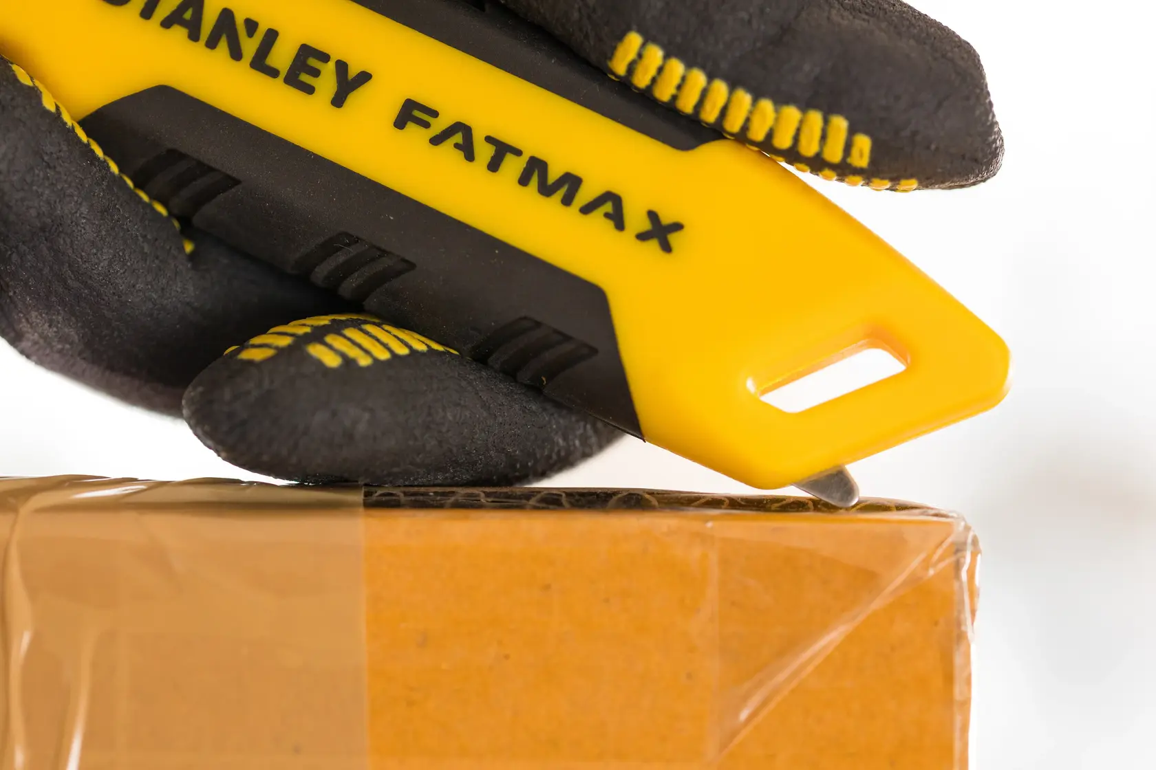 Stanley FMHT10373-0 Messer schneidet Klebeband auf Karton, gelber Griff, Nahaufnahme.
