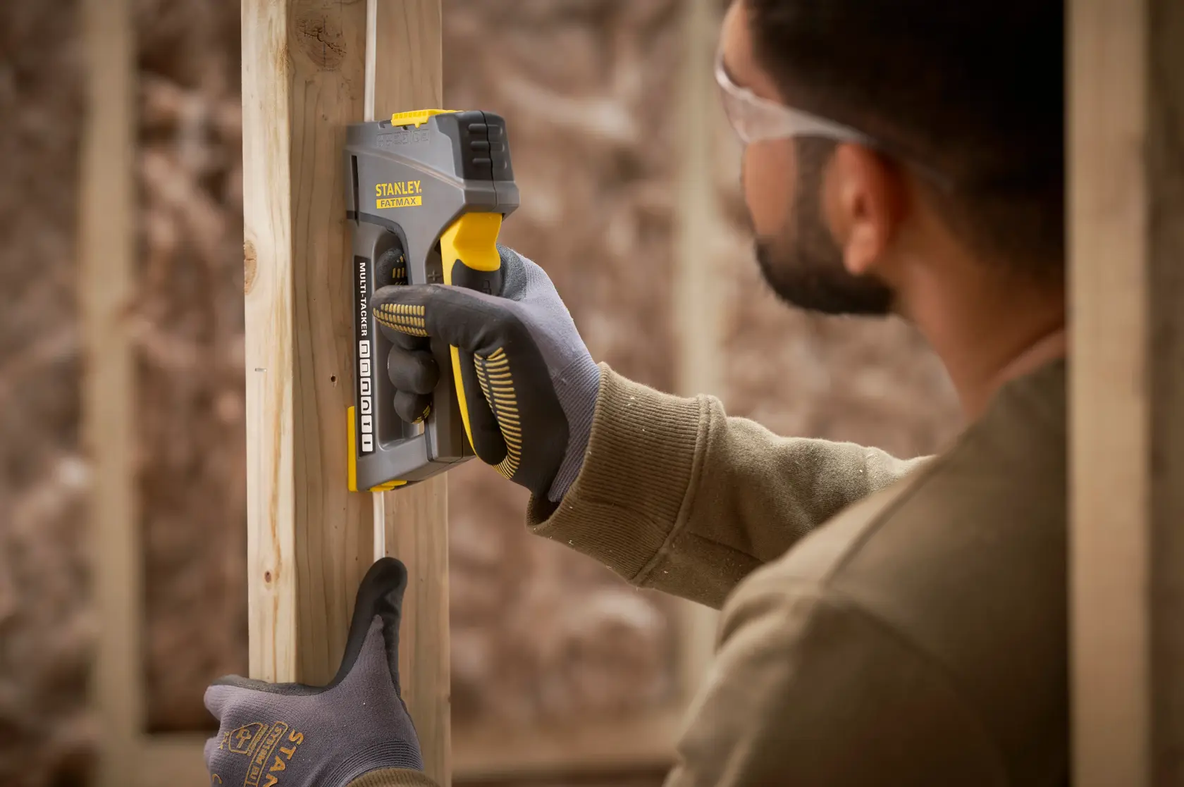 STANLEY FMHT6-70868 Tacker im Einsatz an Holzrahmen, Nahaufnahme Fotografie von Werkzeug und Handschuh.