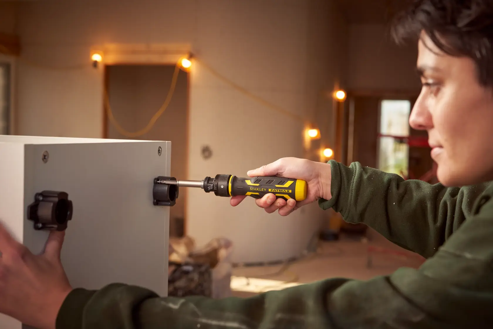 Stanley FMHT62692-0 Ratschen-Schraubendreher montiert Hardware an einem Schrank in einer Werkstatt.