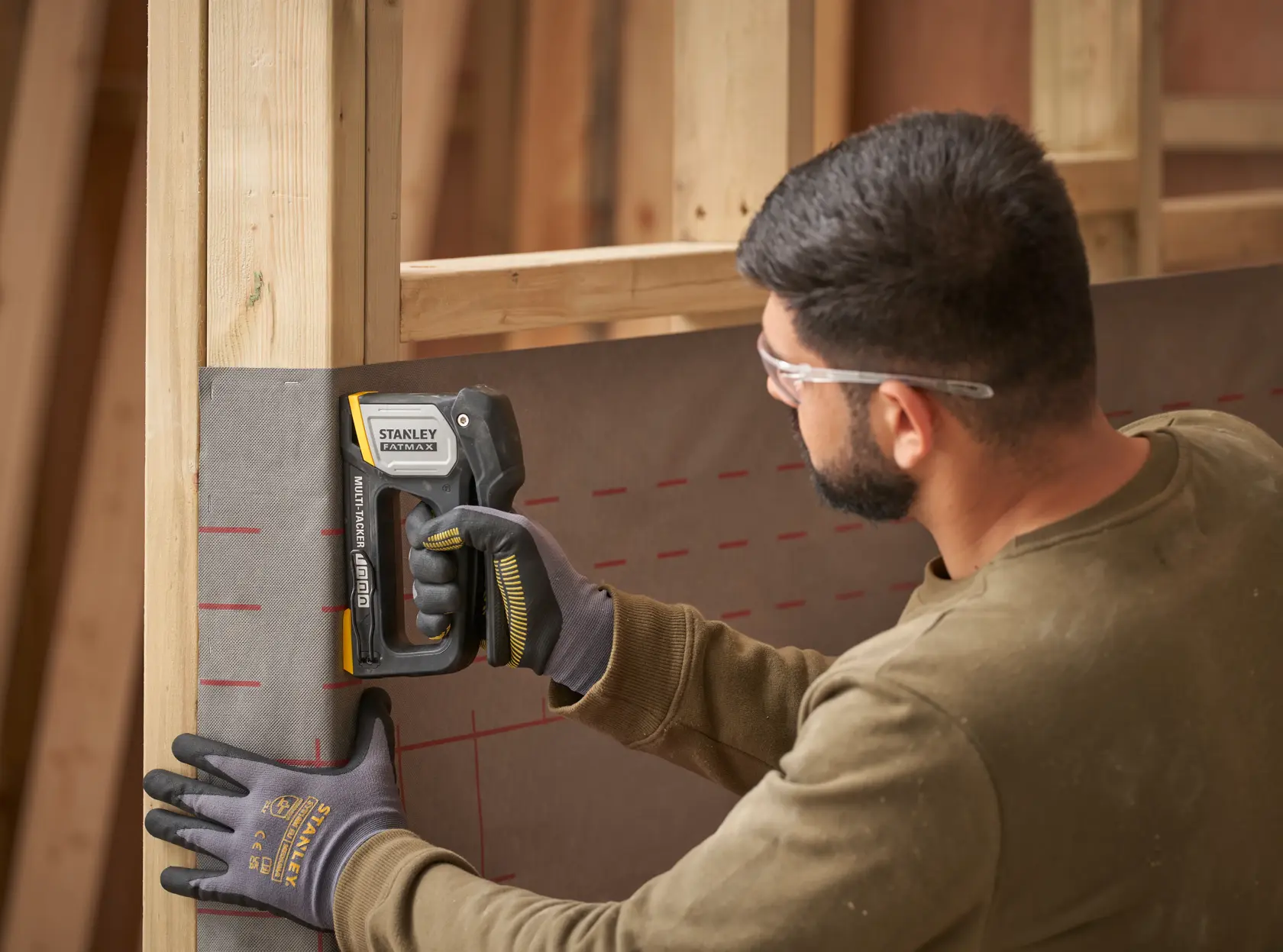 STANLEY FMHT70401-0 Tacker wird auf einer Baustelle verwendet, um Material an einem Holzrahmen zu befestigen.