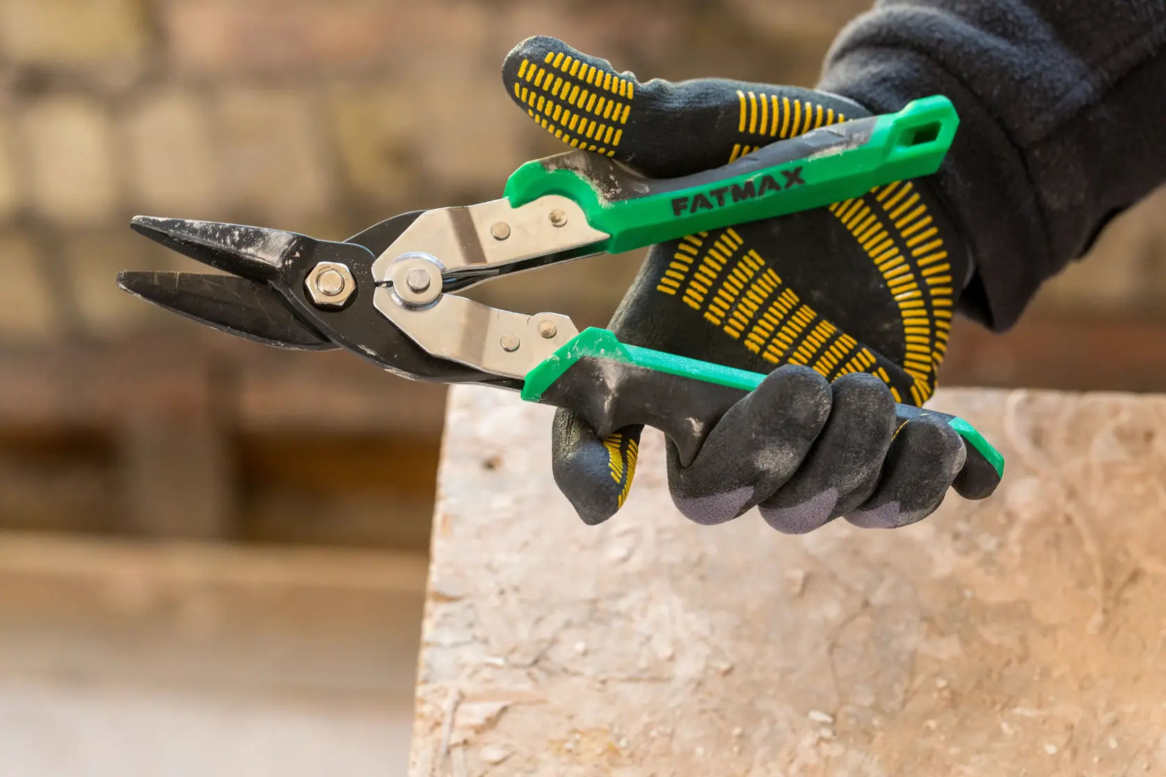 STANLEY FMHT73557-0 grün griff Luftschere in einer behandschuhten Hand, Nahaufnahme.