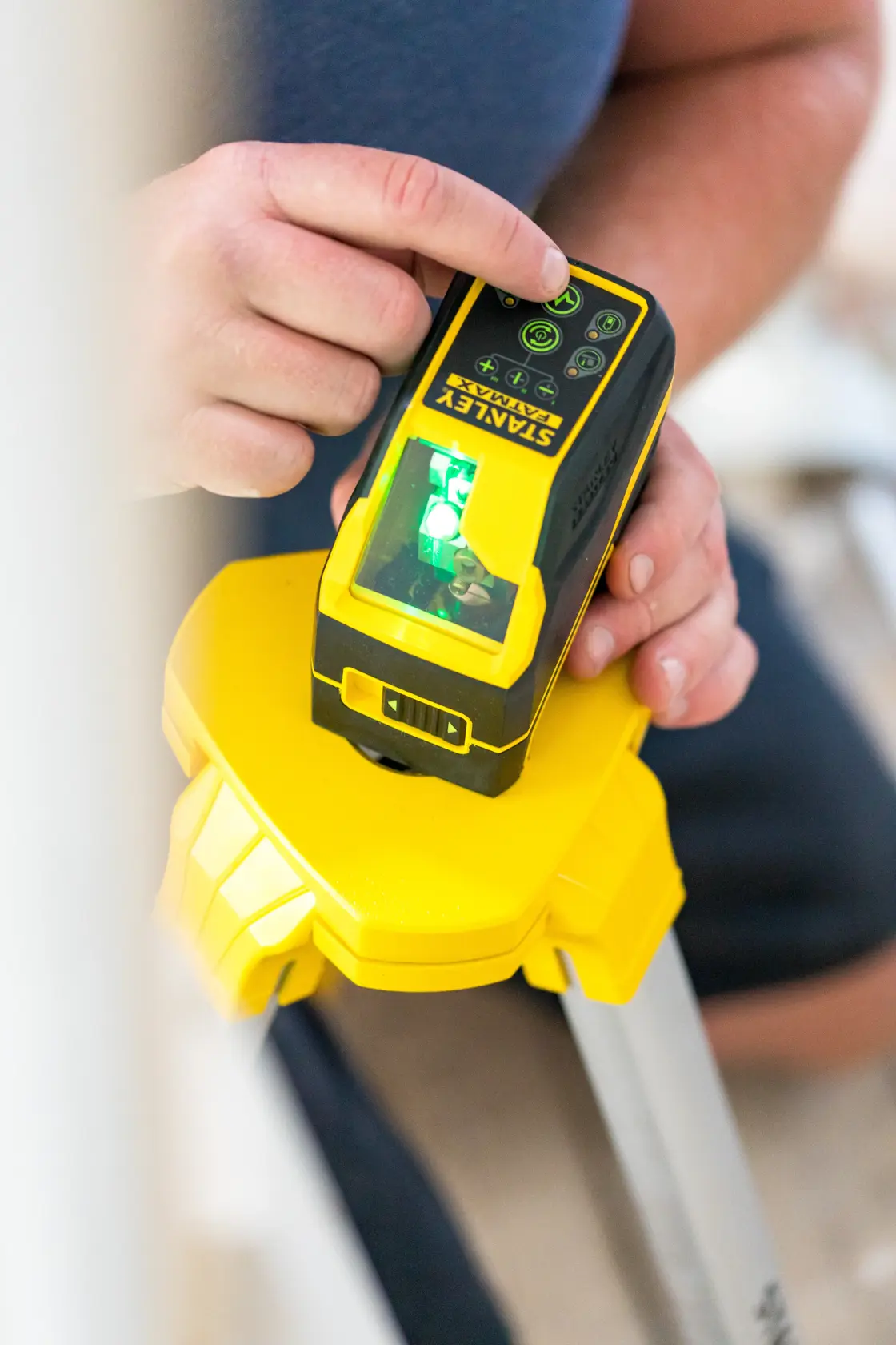 STANLEY FMHT77586-1 Laser-Nivelliergerät auf Stativ, Nahaufnahme einer Hand beim Einstellen der Bedienelemente.