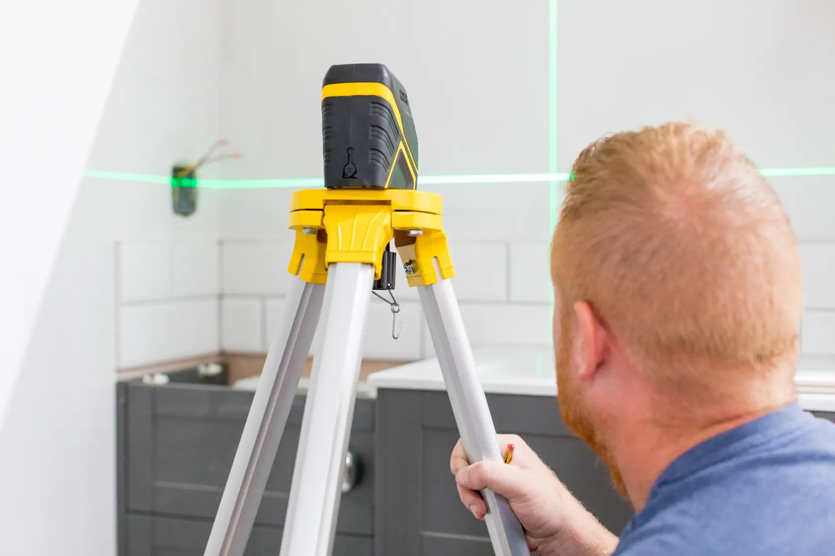 STANLEY FMHT77595-1 Laser-Nivelliergerät auf Stativ in Küche, grüne Laserlinien an der Wand.