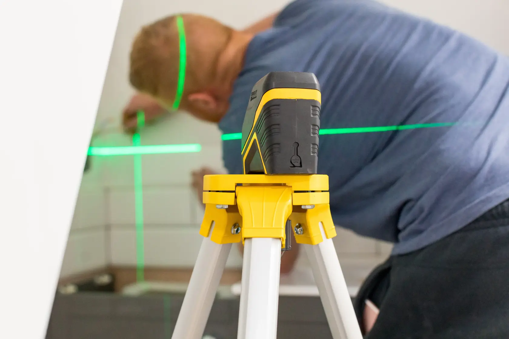 Foto des STANLEY FMHT77595-1 Laser-Nivelliergeräts auf Stativ mit grünen Linien im Innenbereich.