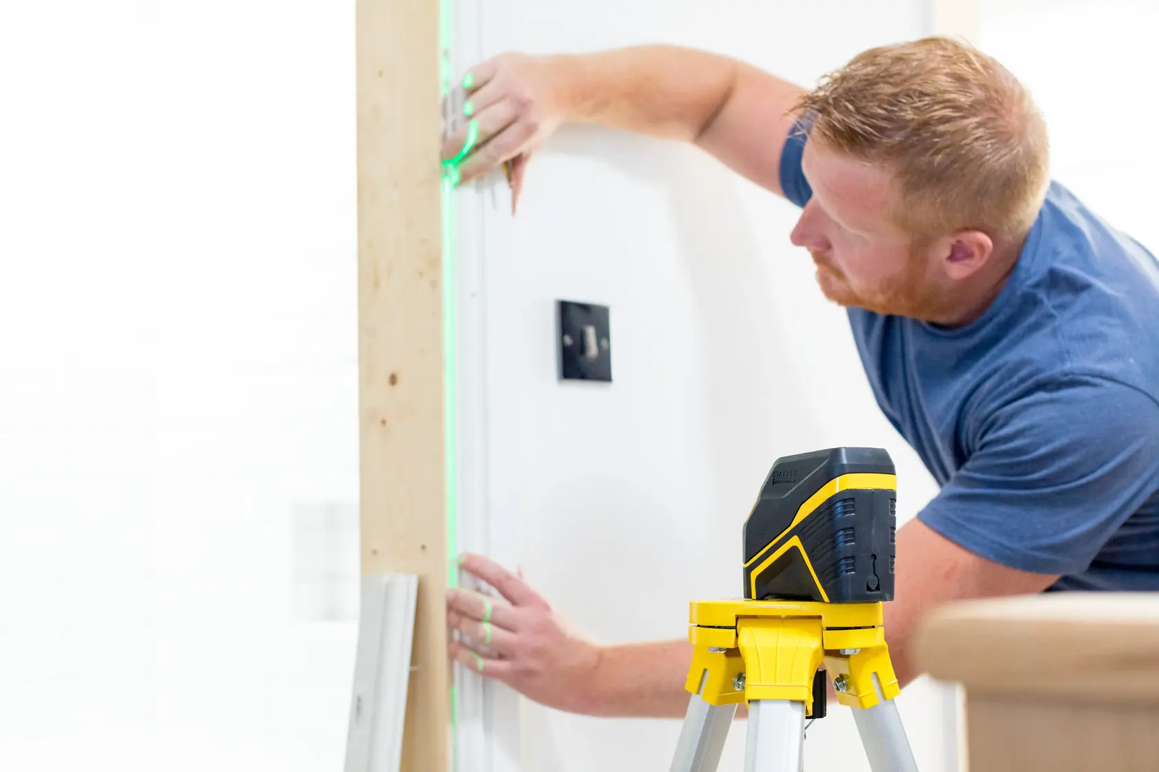 STANLEY FMHT77595-1 Laser-Nivelliergerät auf Stativ, grüne Linie auf Wand bei Installationsarbeiten.
