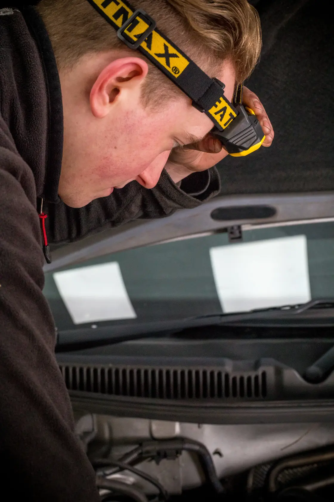 Foto der STANLEY FMHT81509-0 Stirnlampe, getragen bei der Inspektion eines Auto-Motors.