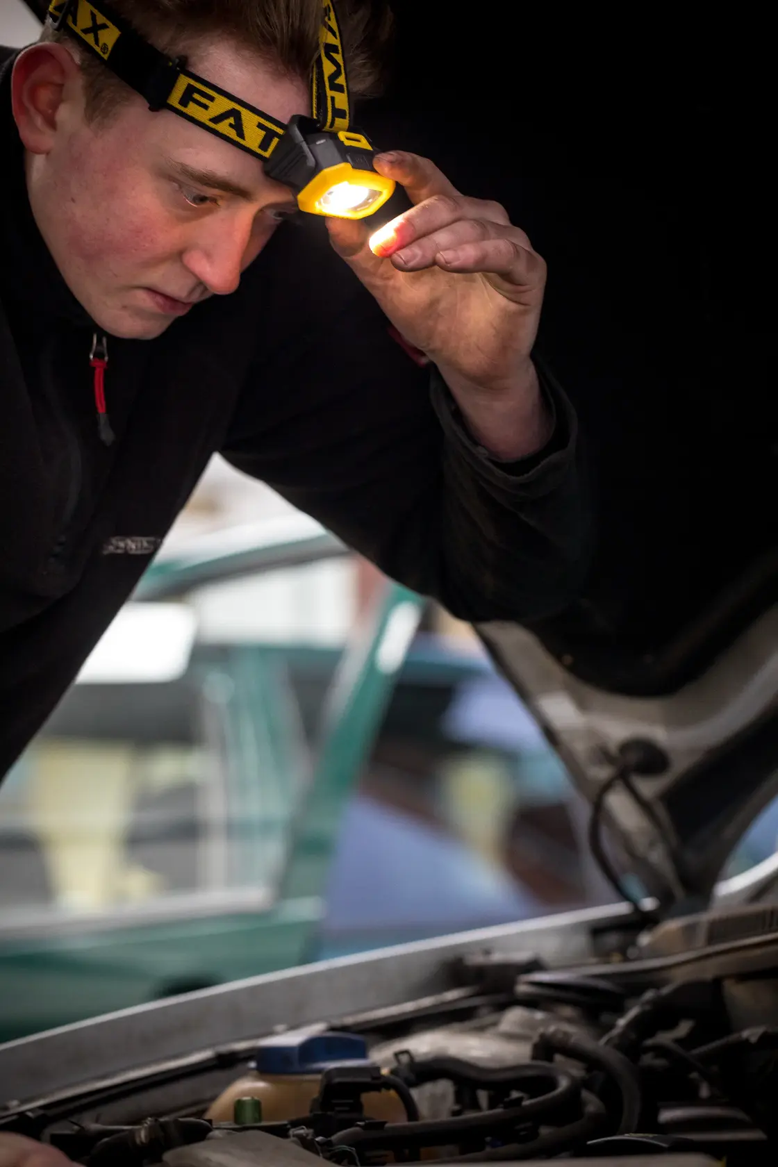 STANLEY FMHT81509-0 Stirnlampe bei Motorinspektion von Person, Nahaufnahme Fotografie.