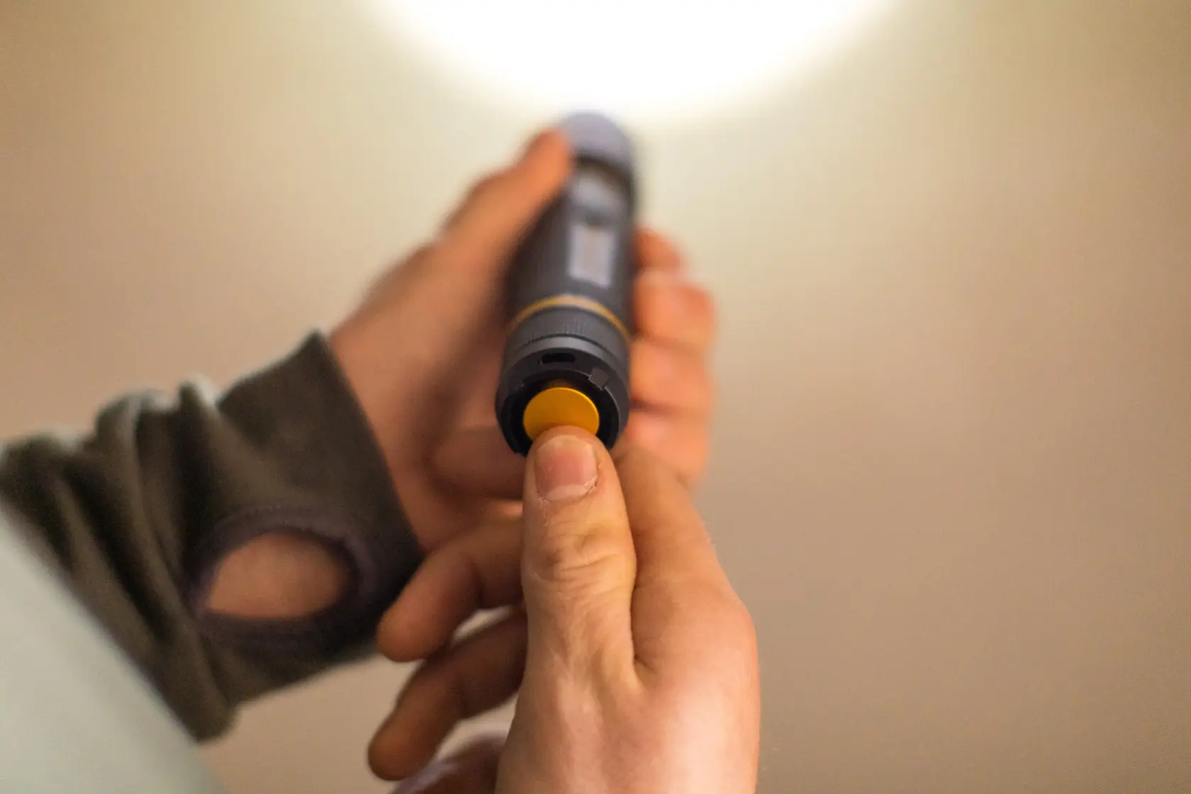 STANLEY FMHT81511-0 Taschenlampe in der Hand, gelber Knopf gedrückt, Nahaufnahme Fotografie.