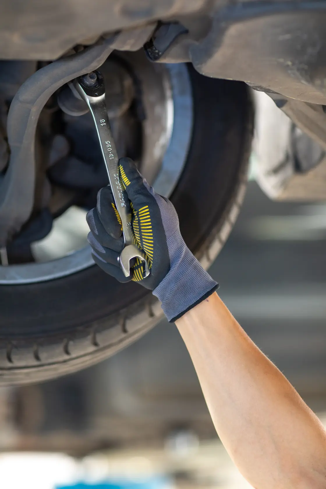 STANLEY FMMT13094-0 Schraubenschlüssel in Handschuh Hand zieht Bolzen unter Fahrzeug an, Vorderansicht.