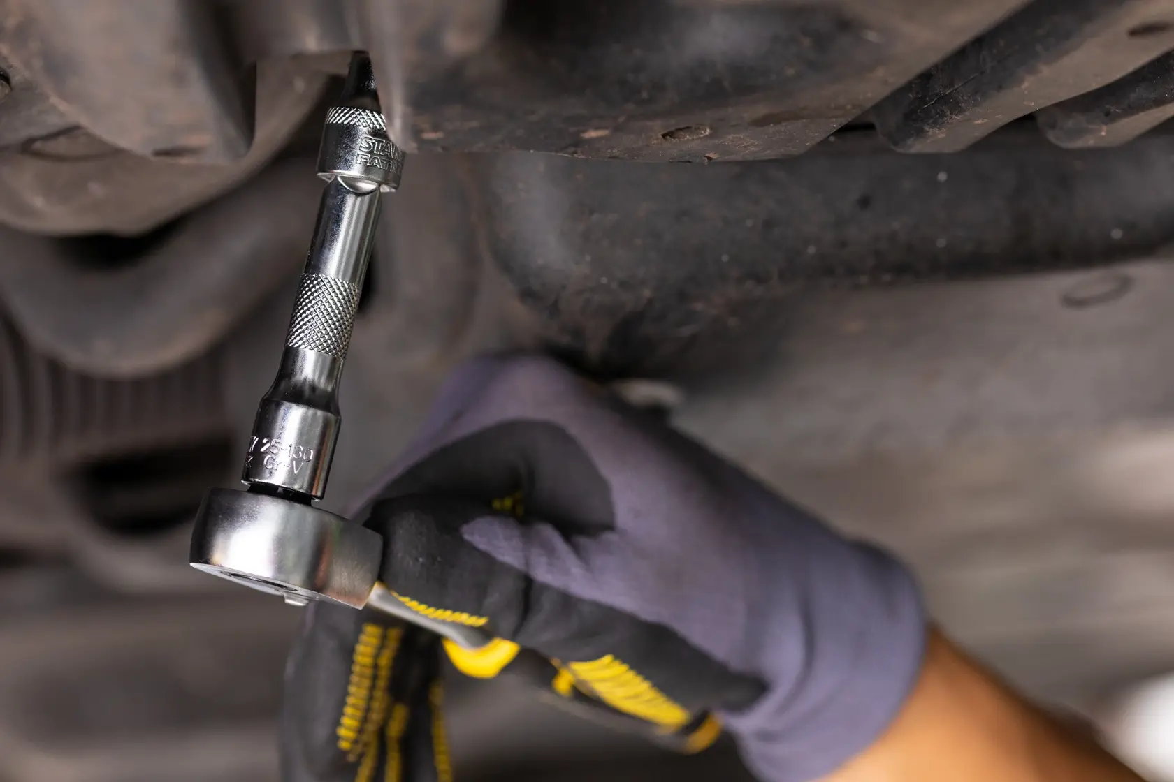 STANLEY FMMT25125-0 Ratsche an einer Schraube, Nahaufnahme, Autoreparatur, behandschuhte Hand.