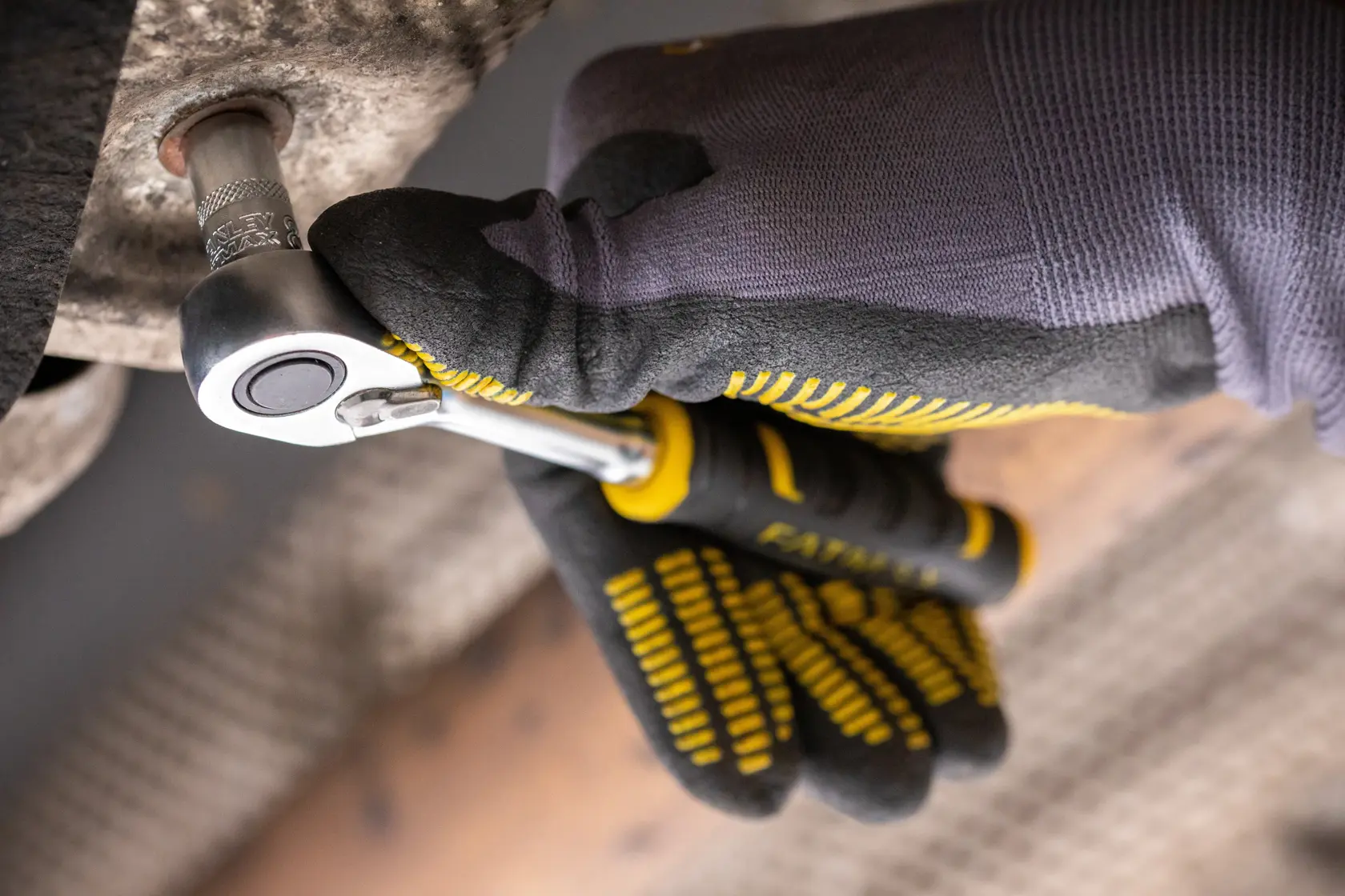 STANLEY FMMT82676-0 Knarrenschlüssel im Einsatz, Nahaufnahme mit behandschuhter Hand, die eine Schraube anzieht.