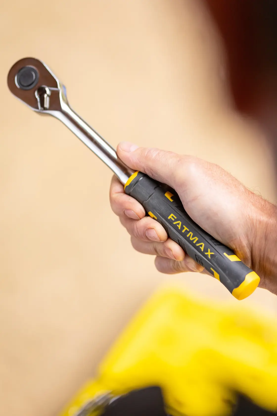 STANLEY FMMT82685-1 Ratschen-schlüssel mit schwarz-gelbem FATMAX Griff in der Hand gehalten, Seitenansicht.