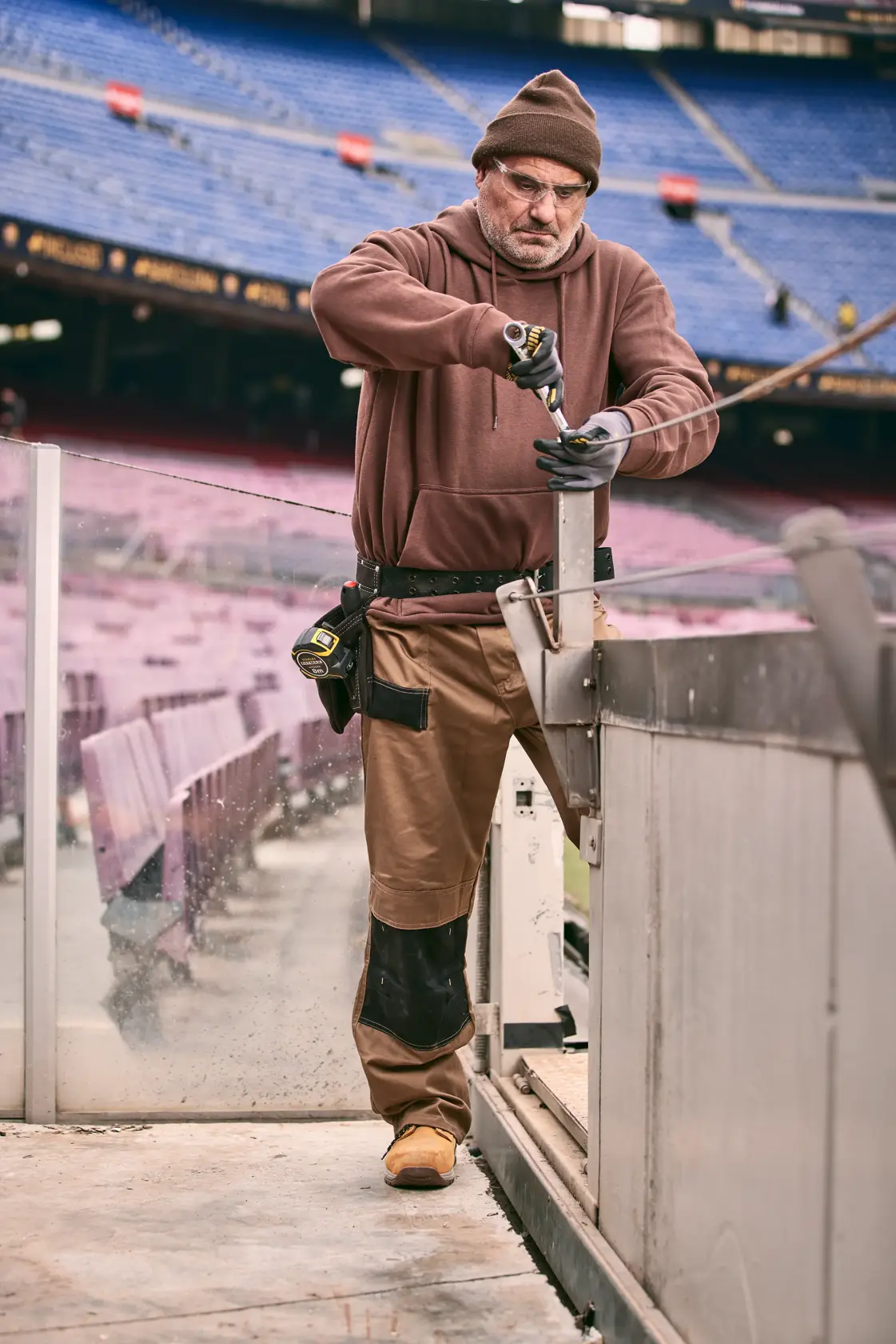 Foto eines Arbeiters mit STANLEY FMMT82848-0 Schraubendreher im Stadion, Werkzeuggürtel und Handschuhen.