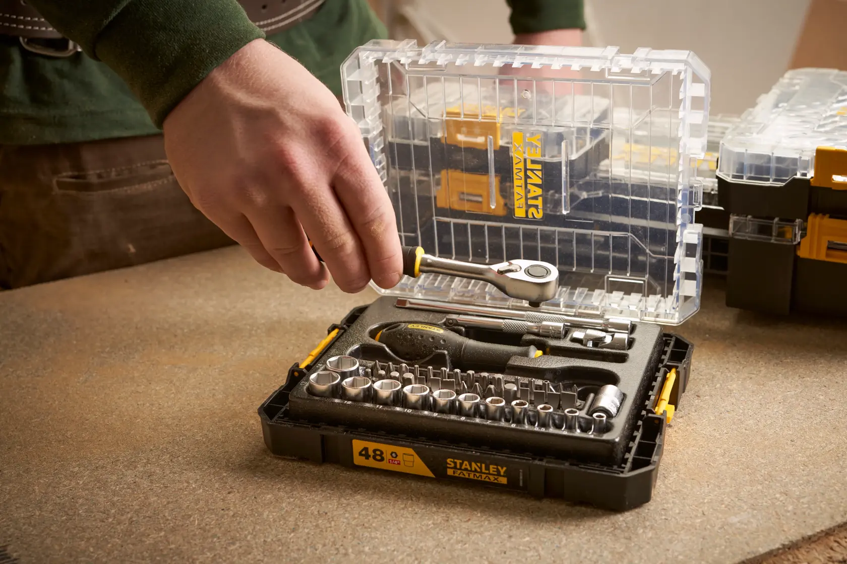 Foto des STANLEY FMMT98101-0 Steckschlüssel- und Ratschen-Werkzeugsets in transparenter Kunststoffbox auf Werkbank.