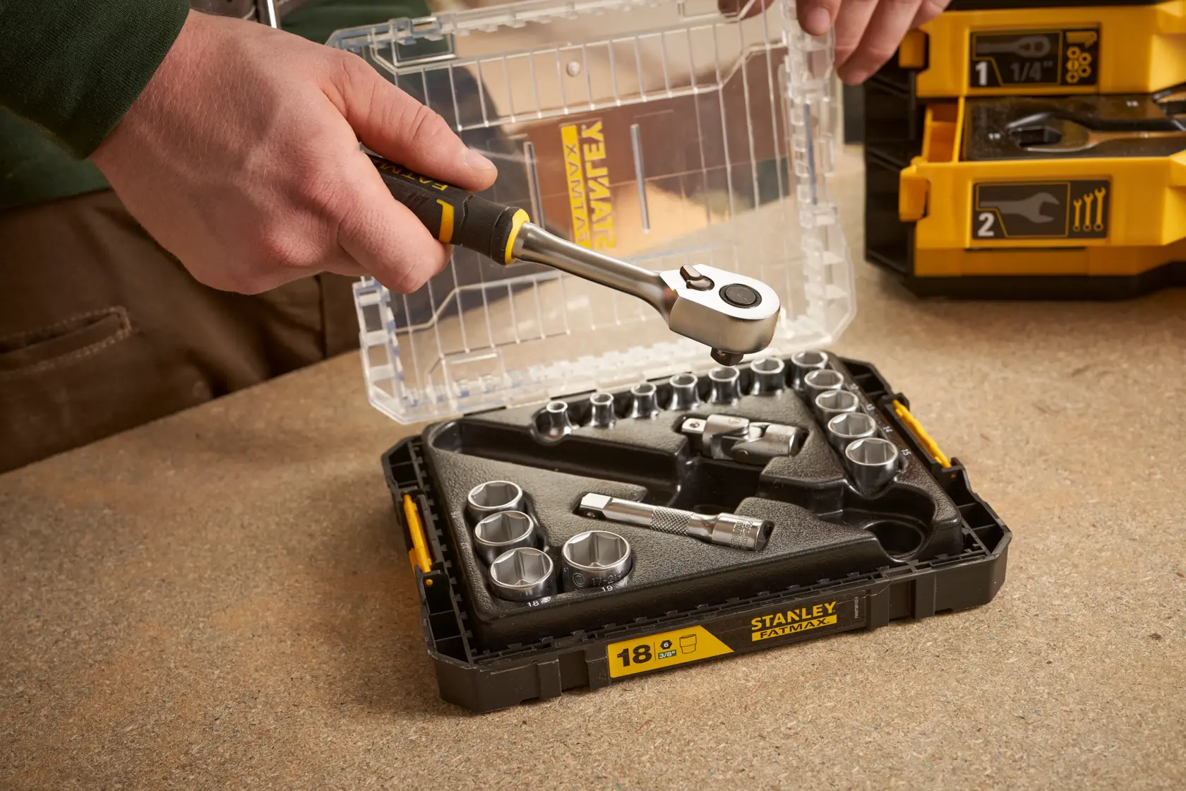 STANLEY FMMT98102-0 Steckschlüsselsatz geöffnet auf Tisch, Hand hält Ratsche.