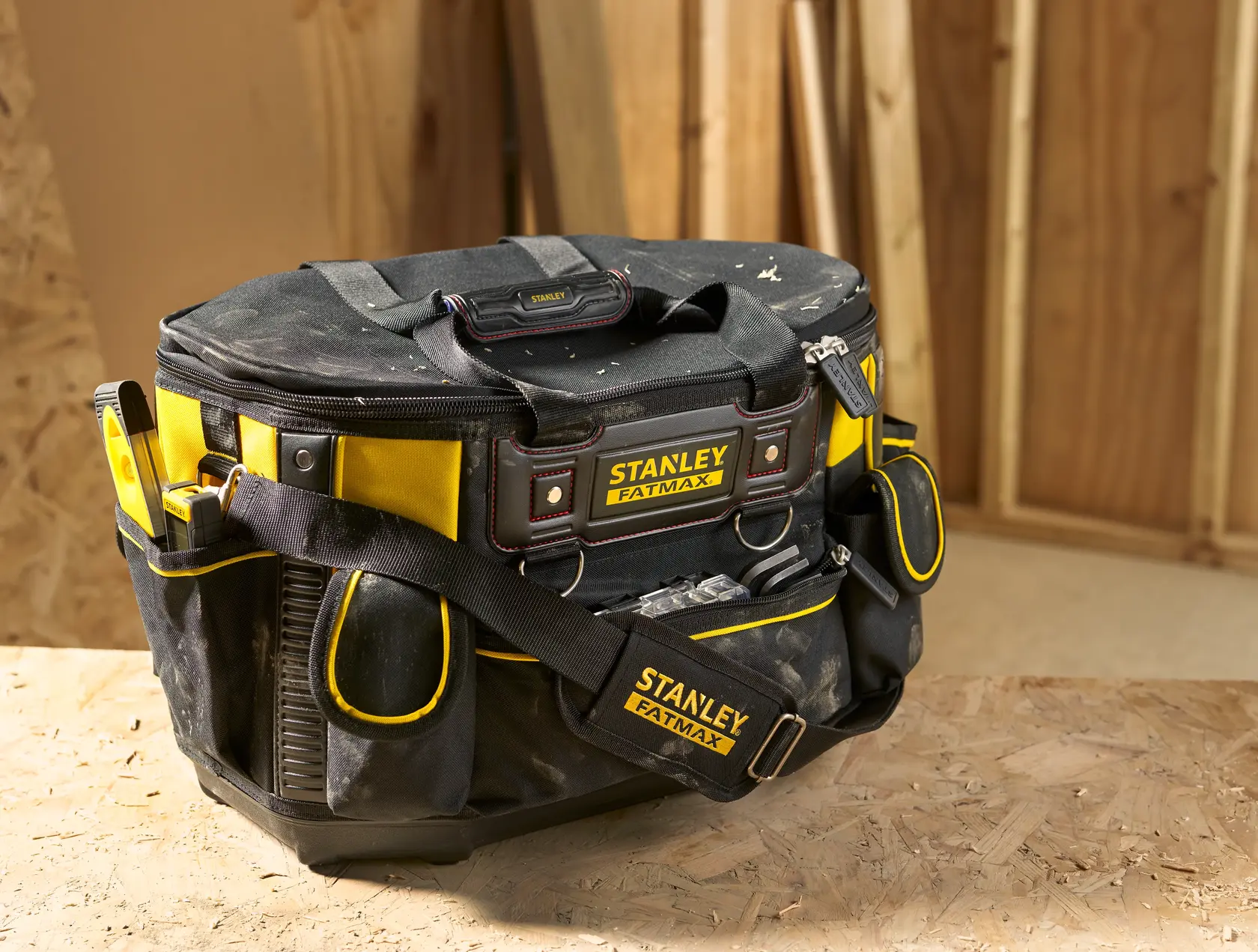 STANLEY FMST1-70749 Werkzeugtasche mit Schulterriemen, schwarz-gelb, auf Holzfläche in Werkstatt.