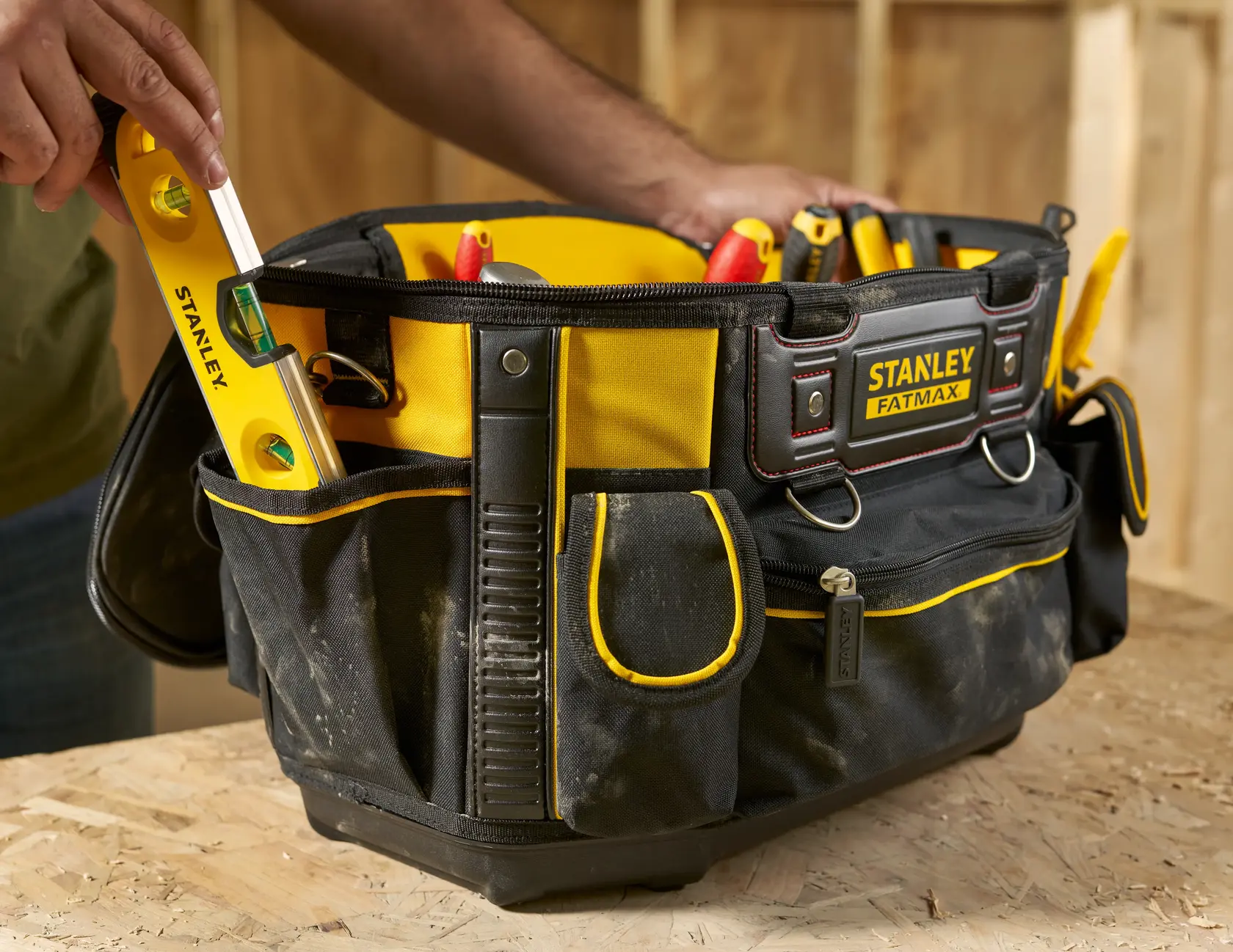 STANLEY FMST1-70749 Werkzeugtasche mit gelben Akzenten, gefüllt mit Werkzeugen, Nahaufnahme auf Werkbank.