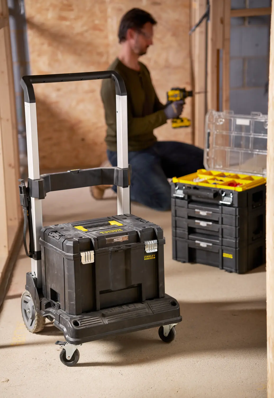 STANLEY FMST1-72363 schwarze Werkzeugbox auf Rollen mit Teleskopgriff in Werkstattumgebung.