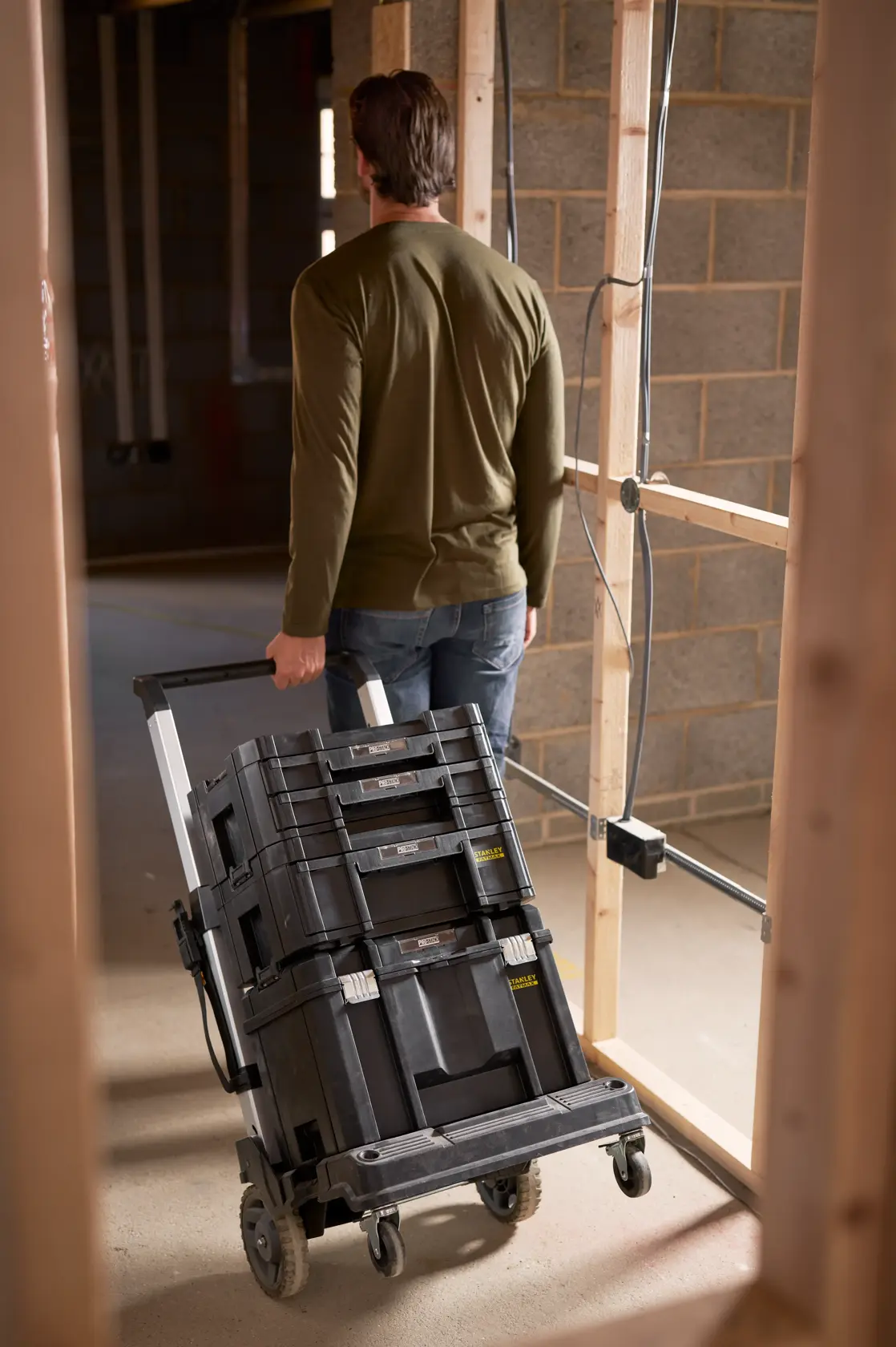 STANLEY FMST1-72363 Rollwagen mit gestapelten Werkzeugkisten auf Baustelle, Rückansicht.