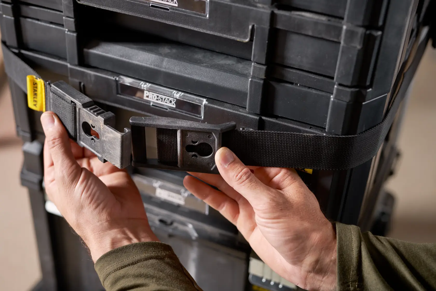 Foto des STANLEY FMST1-72363 Werkzeug-Aufbewahrungsgurts mit Schnalle an schwarzen modularen Werkzeugkisten, Nahaufnahme.
