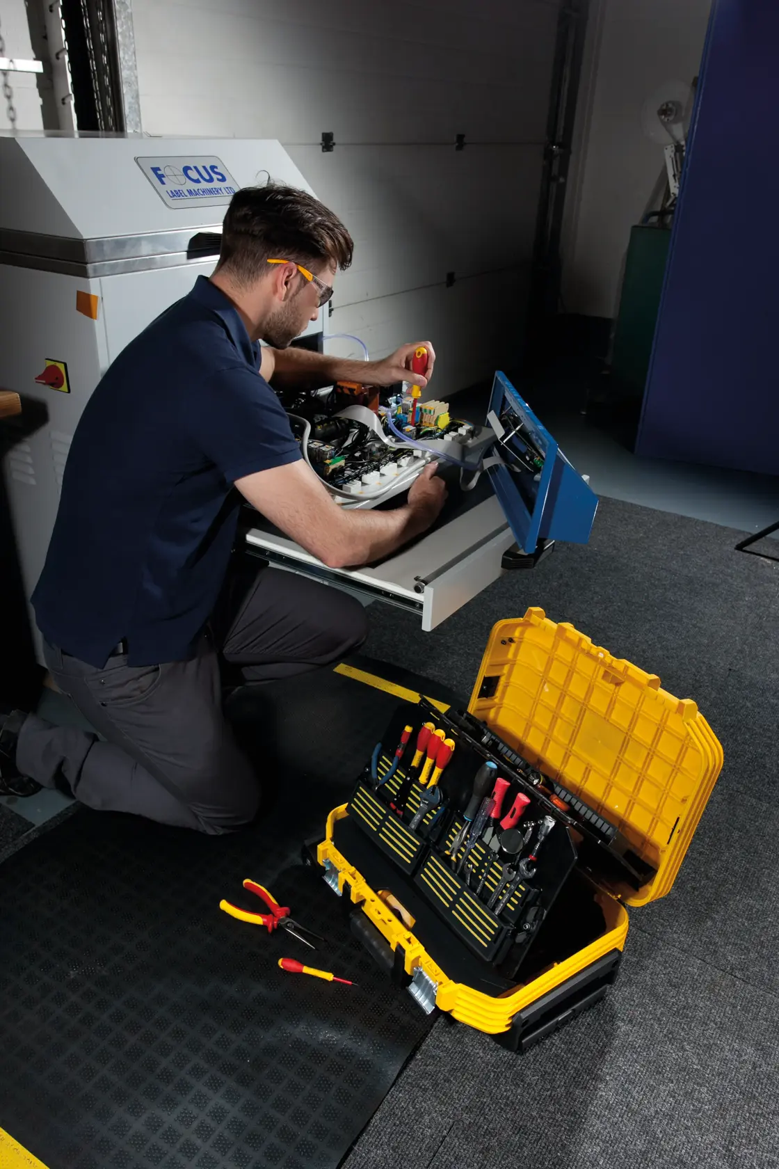 STANLEY FMST1-72383 Werkzeugkasten mit sortierten Handwerkzeugen, offen am Boden neben Techniker bei Reparatur.