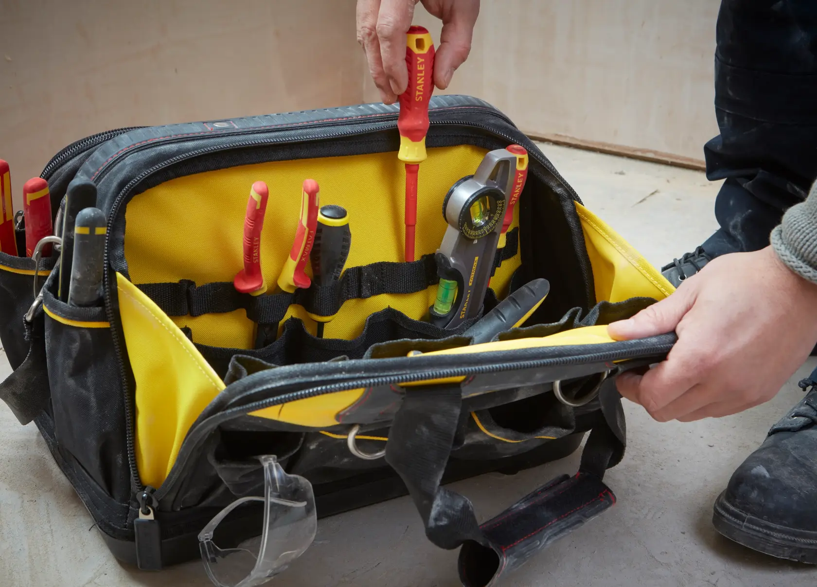 STANLEY FMST1-73607 Werkzeugtasche mit gelbem Innenraum, gefüllt mit Handwerkzeugen und Schutzbrille.