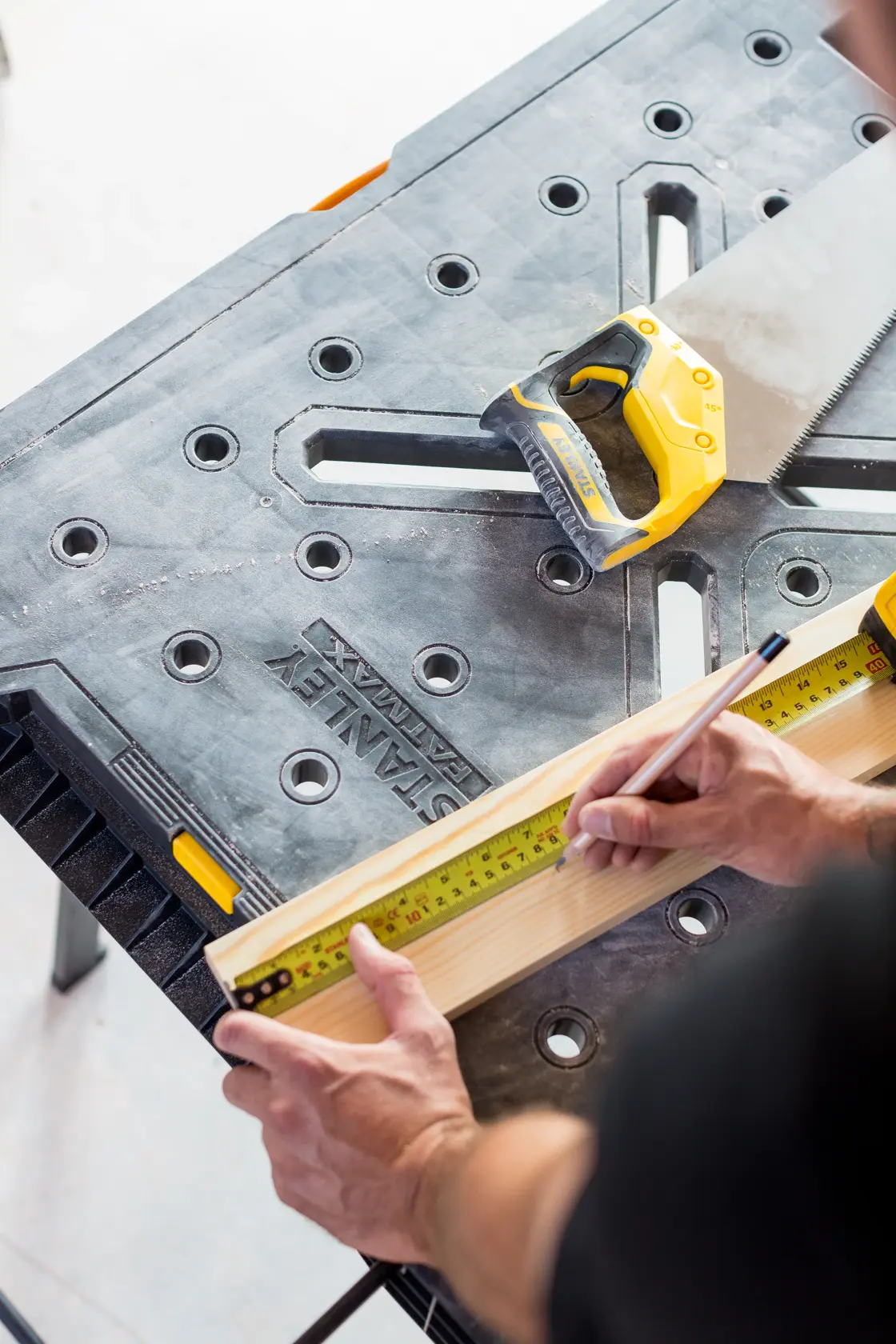 STANLEY FMST1-75672 Werkbank mit Handsäge und Maßband, Holz wird zum Schneiden markiert.