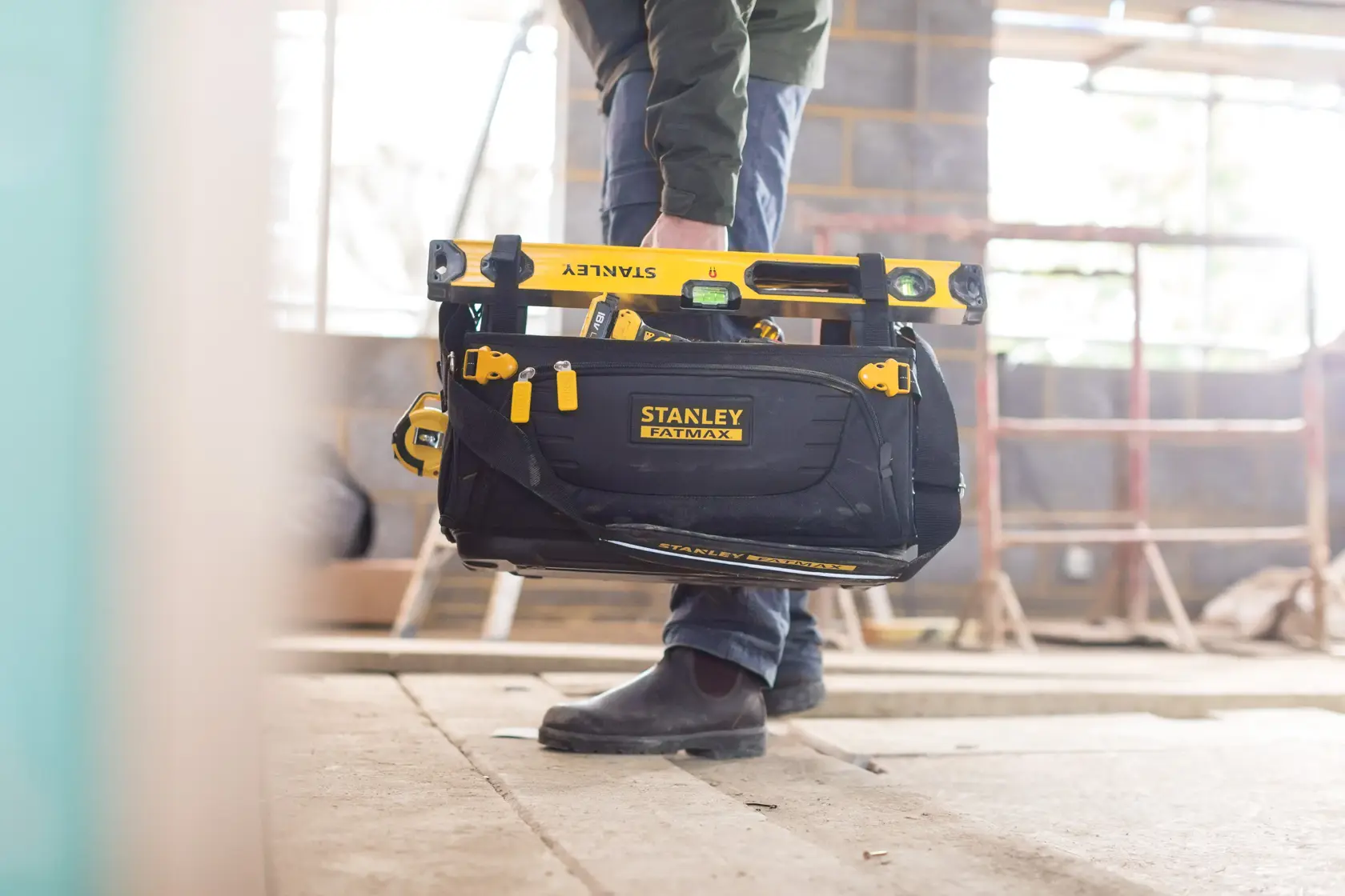 Foto der STANLEY FMST1-80146 FATMAX Werkzeugtasche mit gelben Werkzeugen auf einer Baustelle.