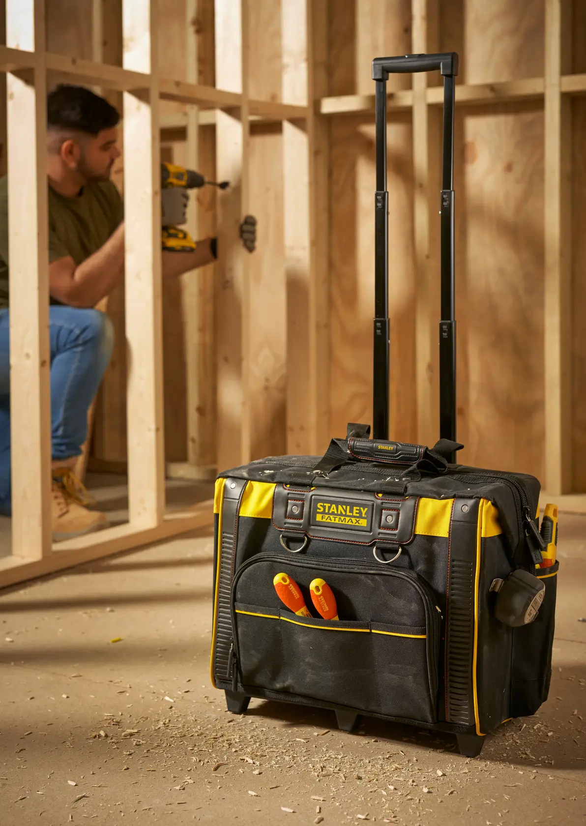 STANLEY FMST1-80148 Rollwerkzeugtasche mit ausgezogenem Griff, schwarz-gelb, auf Baustellenboden.