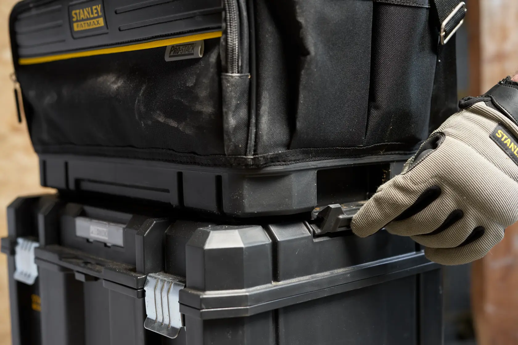 STANLEY FMST17627-1 Werkzeugbox Nahaufnahme, gestapelte modulare Kisten, behandschuhte Hand am Verschluss, Seitenansicht.