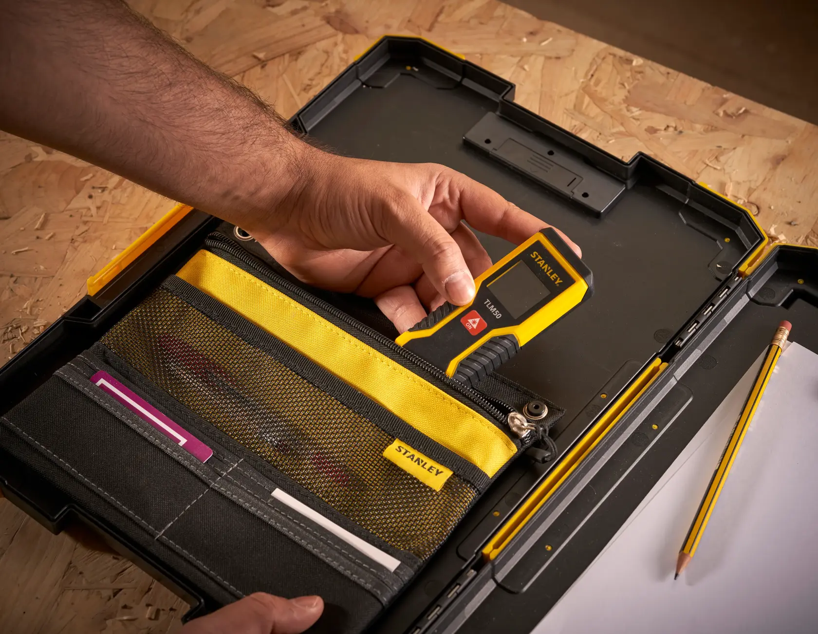 Foto des STANLEY FMST82721-1 Werkzeugkoffers mit gelbem und schwarzem Organizer, Hand hält digitales Messgerät.