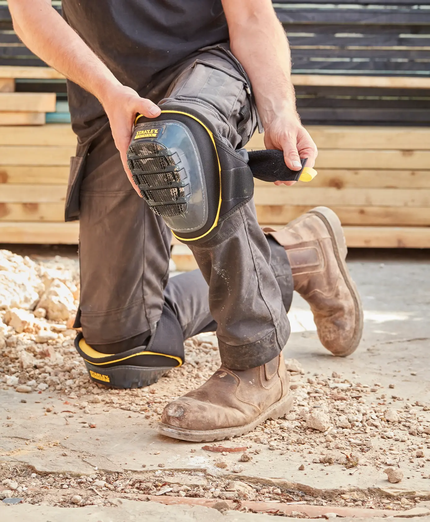 STANLEY FMST82960-1 Knieschoner am Arbeiter beim Knien auf rauem Boden, Nahaufnahme Outdoor-Fotografie.