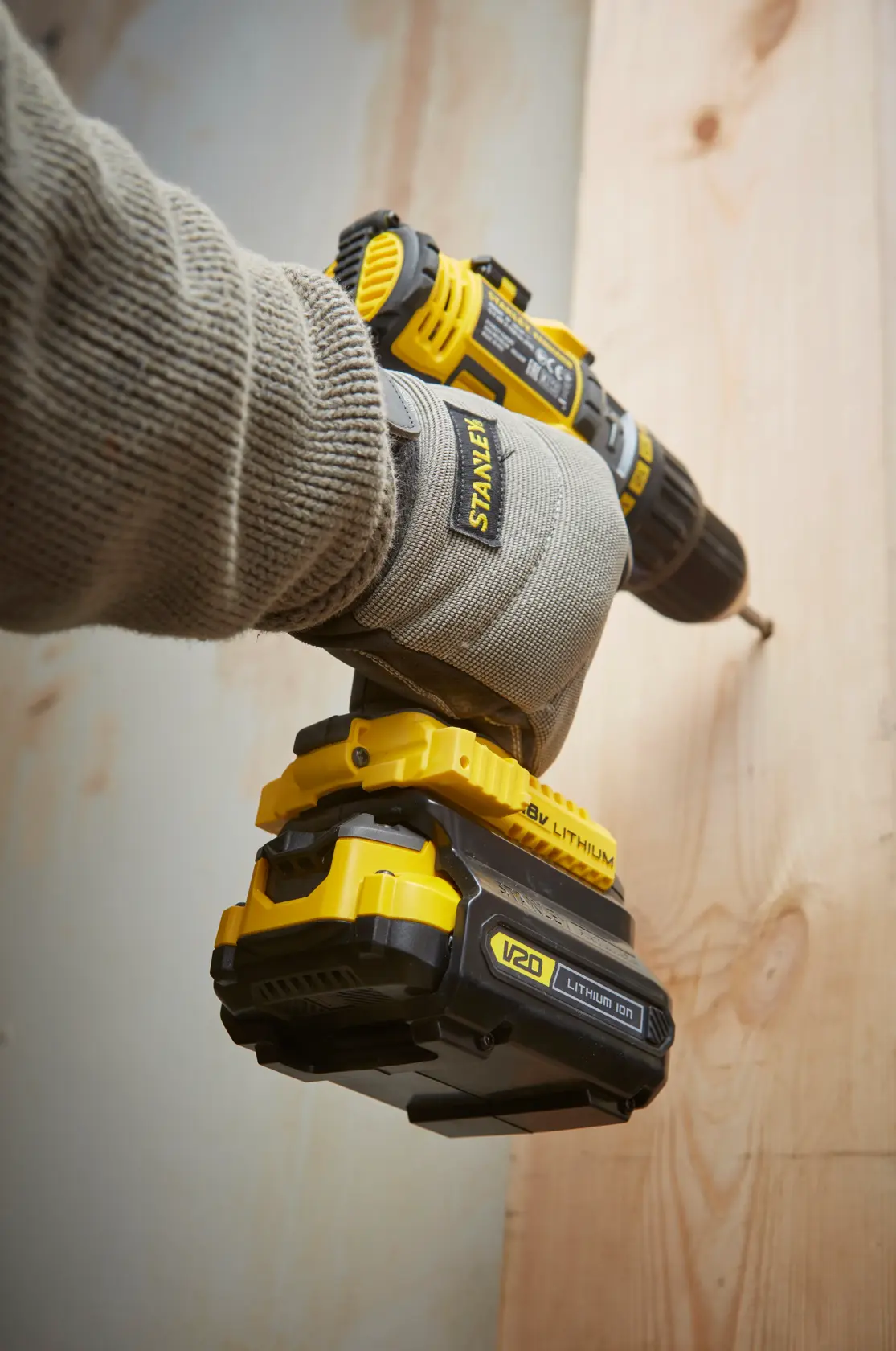 STANLEY SFMCB100 V20 Lithium-Ionen-Bohrmaschine wird von einer behandschuhten Hand ins Holz geschraubt.