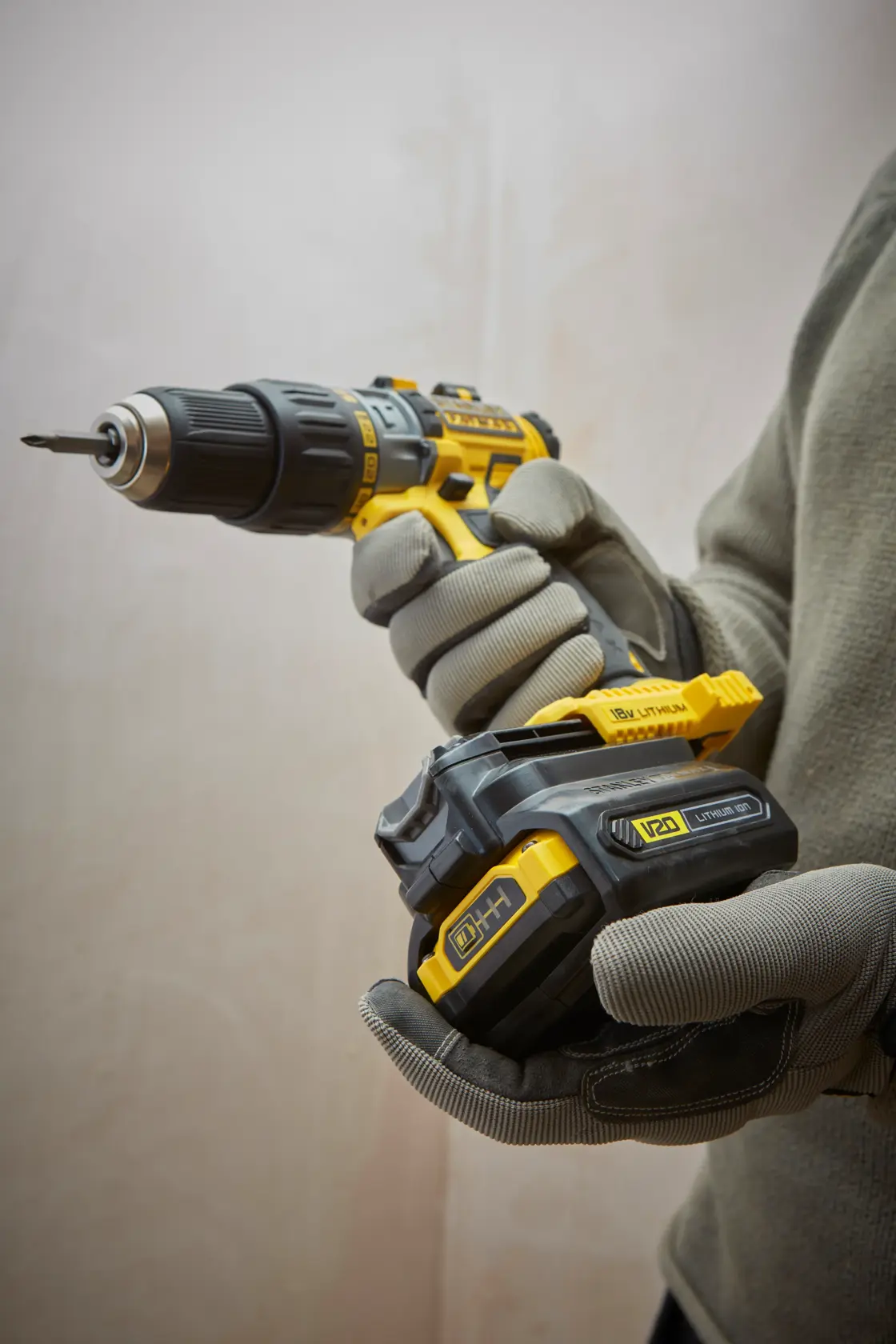 STANLEY SFMCB100 Akkubohrmaschine mit V20 Lithium-Batterie, Nahaufnahme im Einsatz, graue Handschuhe sichtbar.