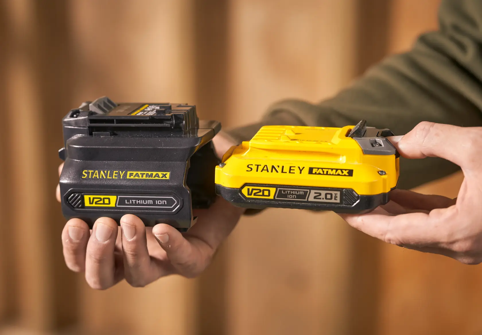 Foto von STANLEY SFMCB121D1 V20 Lithium-Ionen-Akkus, einer schwarz und einer gelb, in der Hand gehalten.