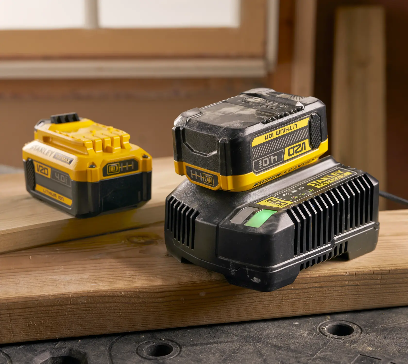Foto von STANLEY SFMCB204 V20 4,0Ah Lithium-Ionen-Akku und Ladegerät, gelb und schwarz auf Holzlatten.