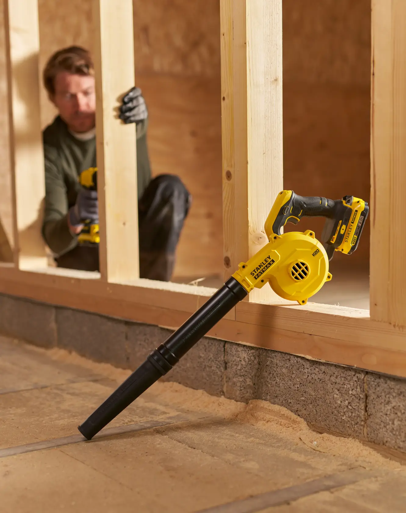 STANLEY SFMCBL01B Akku-Gebläse auf Holzrahmen, gelb-schwarzes Design, Innenbaustelle.