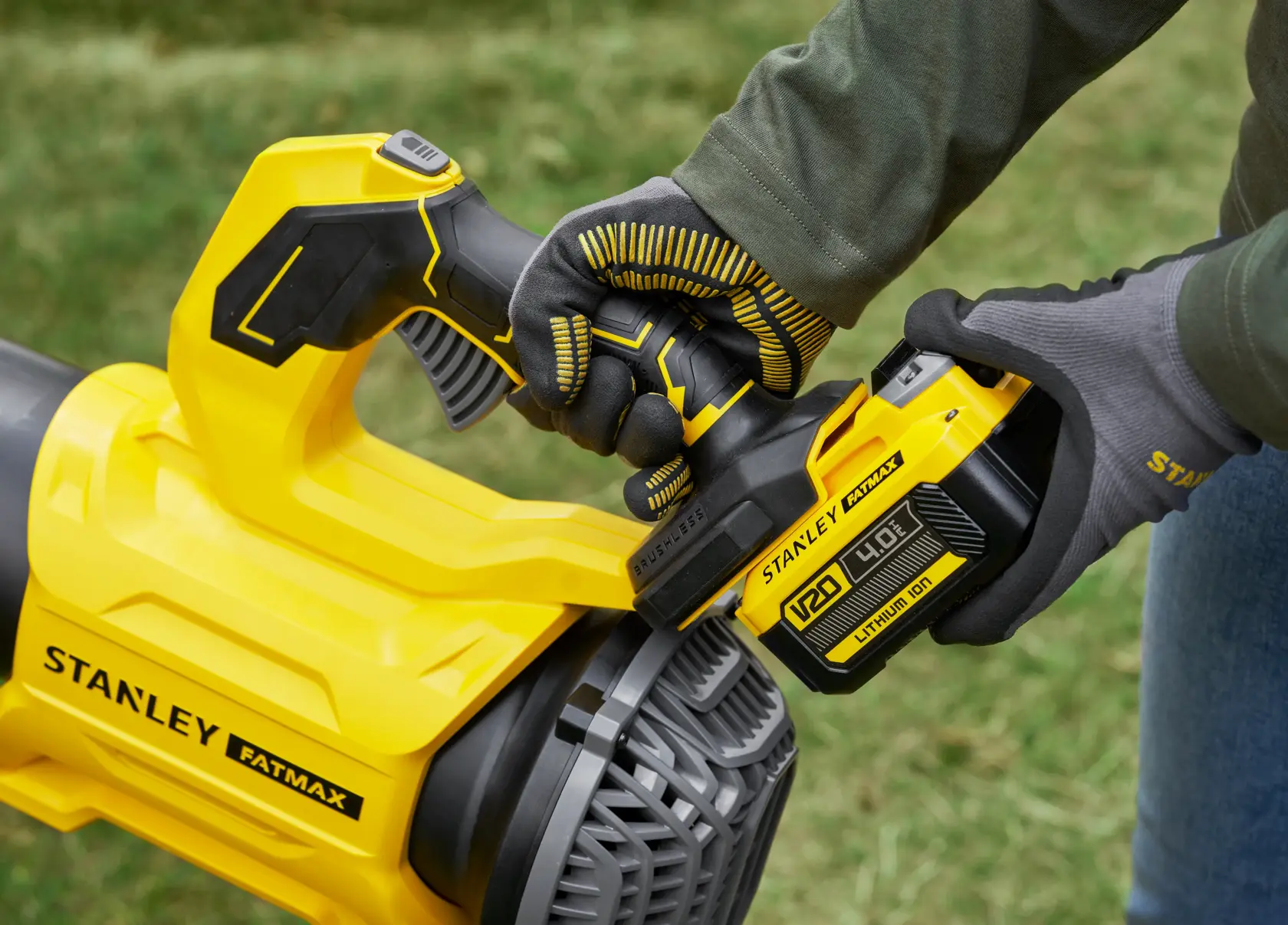 STANLEY SFMCBL730M1 kabelloser Laubbläser Nahaufnahme mit behandschuhter Hand beim Einsetzen des Akkus, draußen.