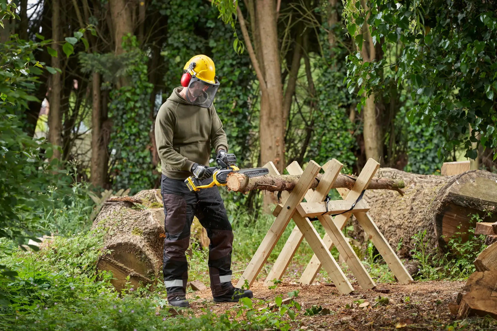 STANLEY SFMCCS730M1 Akku-Kettensäge im Außeneinsatz, schneidet ein Holzstück auf einem Sägebock.