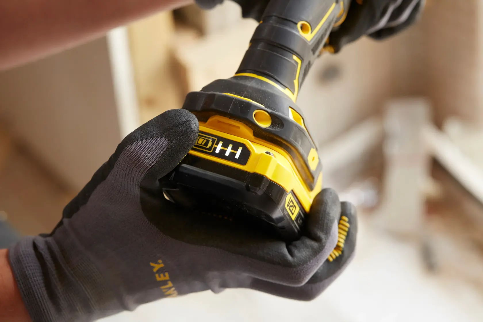 STANLEY SFMCD720B Akkubohrer Nahaufnahme von einer behandschuhter Hand gehalten, gelber und schwarzer Körper sichtbar.