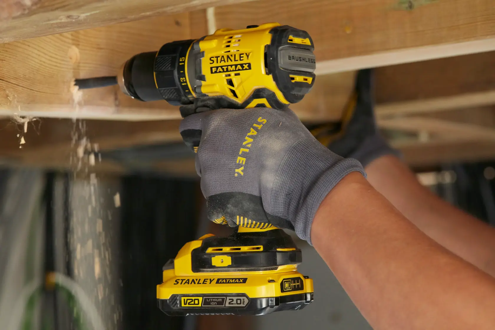 STANLEY SFMCD720B kabellose bürstenlose Bohrmaschine beim Holzbohren, gelb und schwarz, Nahaufnahme.
