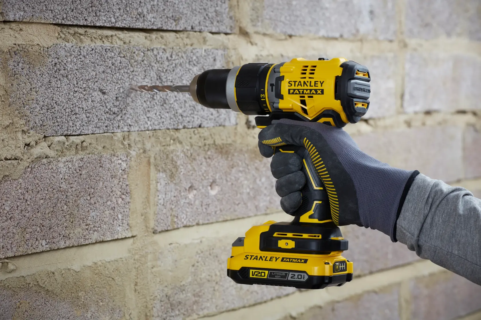STANLEY SFMCD721B Akku-Bohrmaschine im Einsatz an einer Mauerwerkswand, Nahaufnahme seitlich.