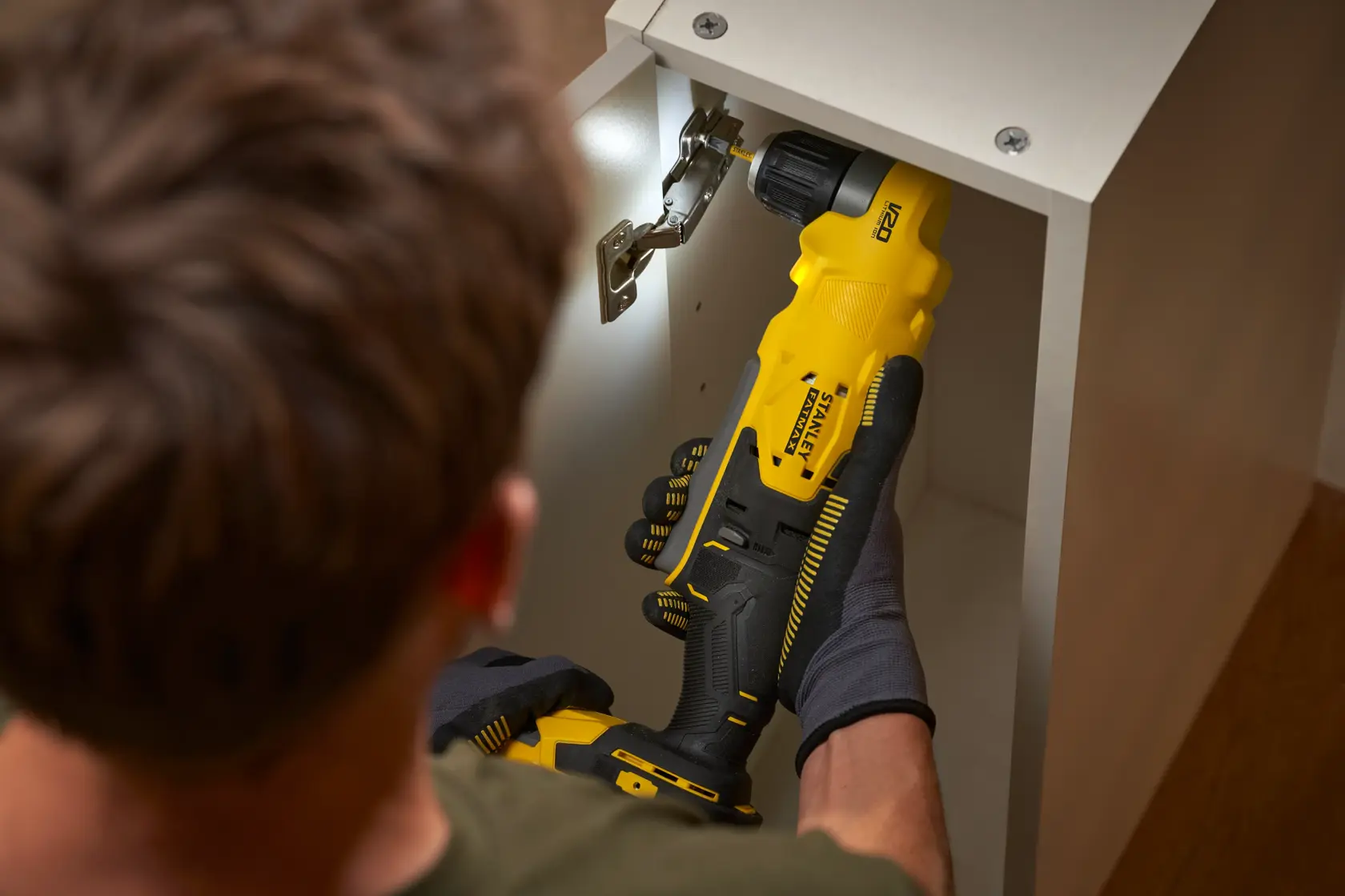 Fotografie des STANLEY SFMCD750B Akku-Bohrers im Einsatz in einem Schrank, Nahaufnahme.