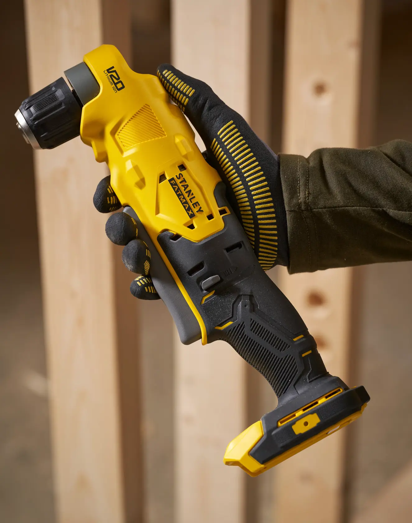 Stanley SFMCD750B kabelloser Winkelbohrer in Gelb und Schwarz, gehalten mit Handschuh, Baustellenumgebung.