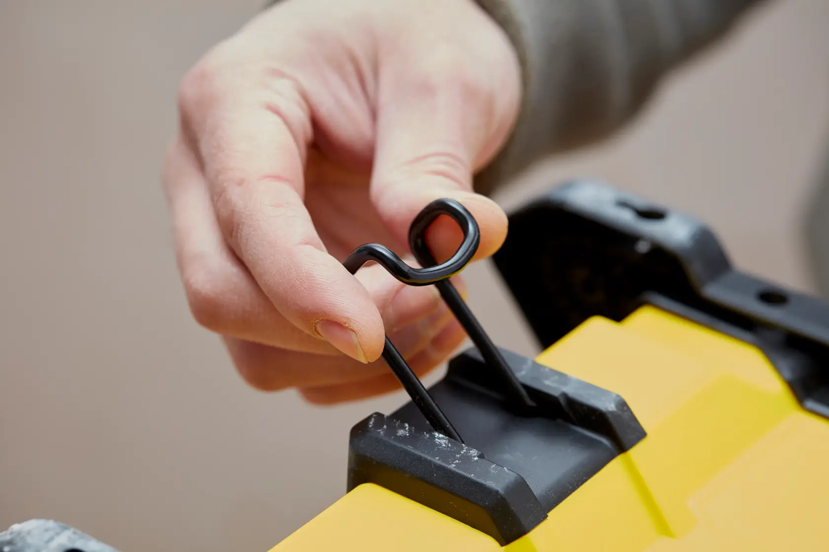 STANLEY SFMCE001B Nahaufnahme einer Hand, die einen schwarzen Metallverschluss auf gelber Produktoberfläche betätigt.