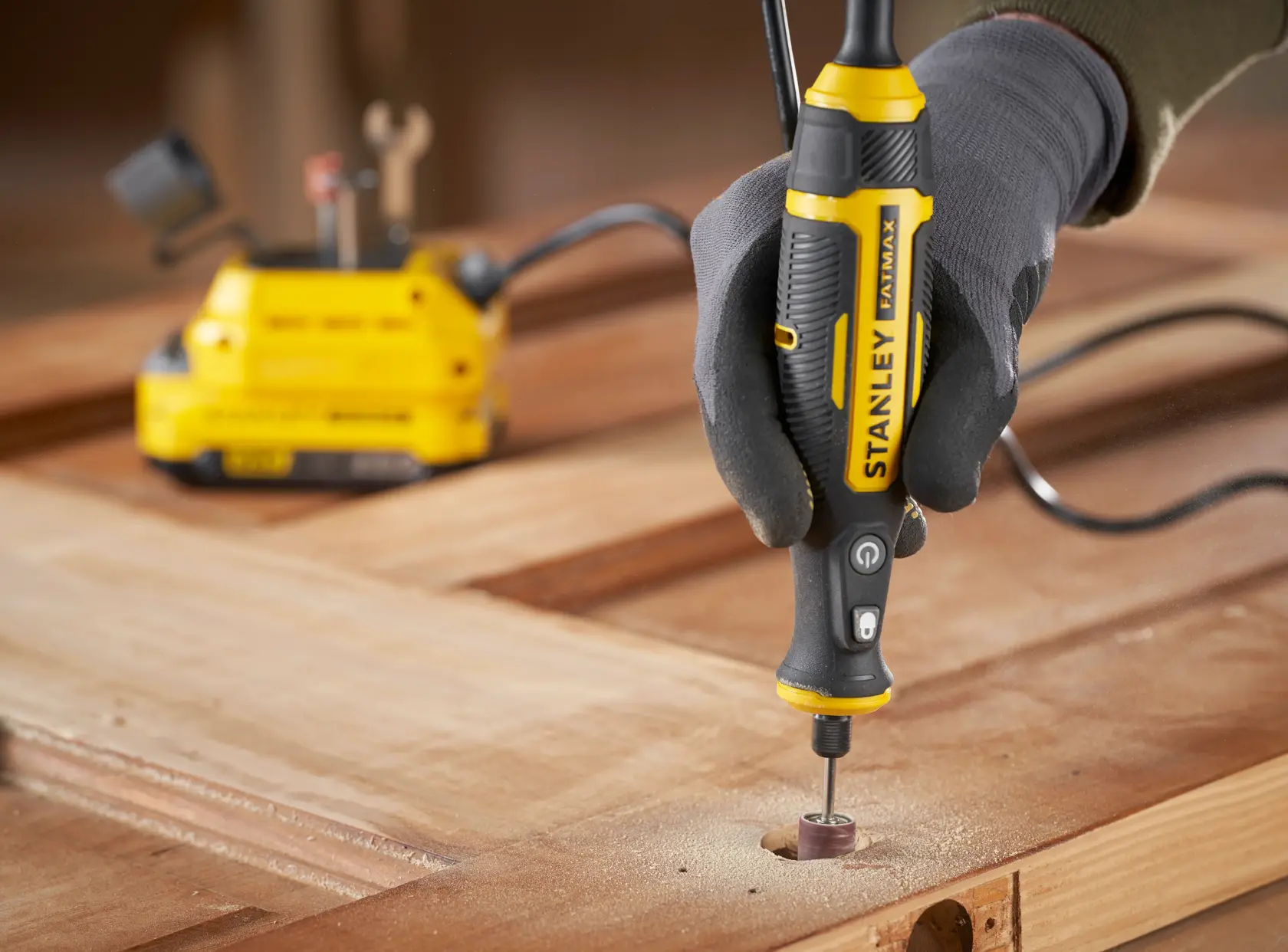 STANLEY SFMCE030B Rotationswerkzeug zum Schleifen von Holz, Nahaufnahme des Werkzeugs in der Hand auf der Arbeitsfläche.