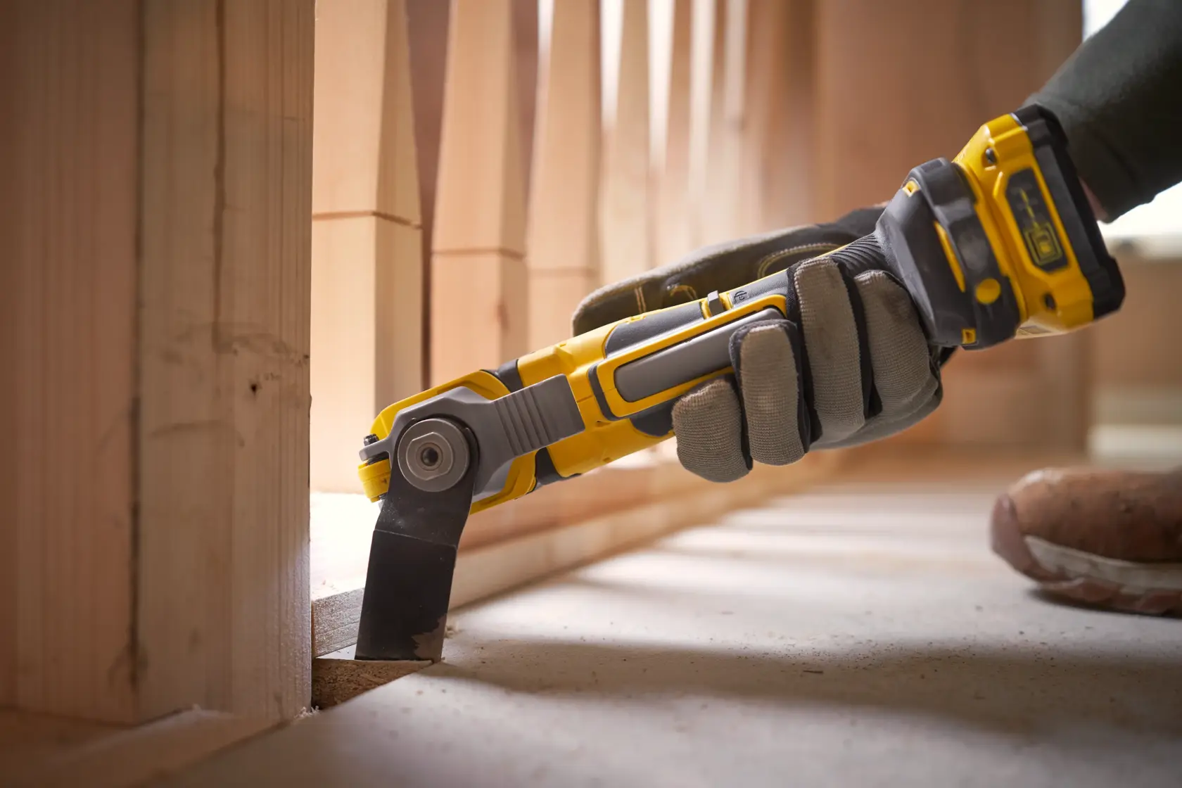 STANLEY SFMCE510B Oszillationswerkzeug im Einsatz, gelb-schwarz, schneidet Holz nahe dem Boden.