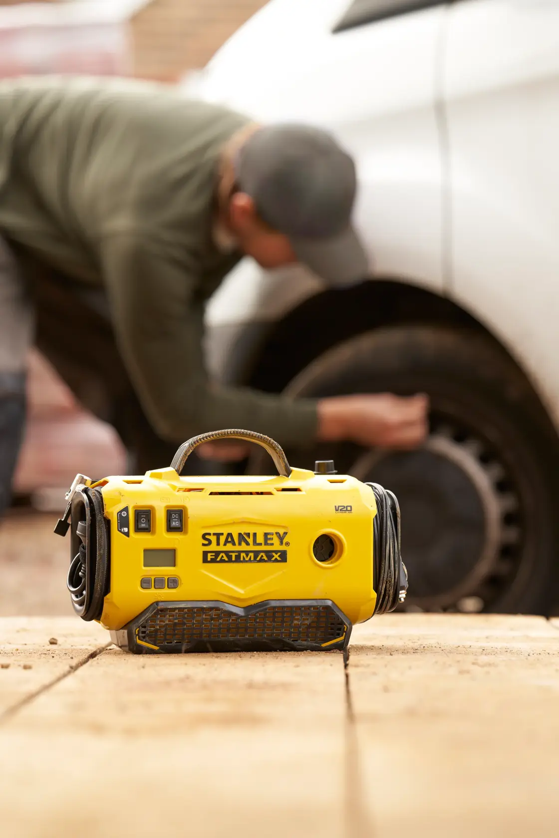 STANLEY SFMCE520B FATMAX gelber tragbarer Kompressor im Freien, eine Person nutzt ihn am Autoreifen.